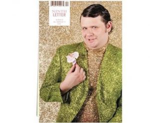Man in green glitter suit jacket with flower and gold glitter background