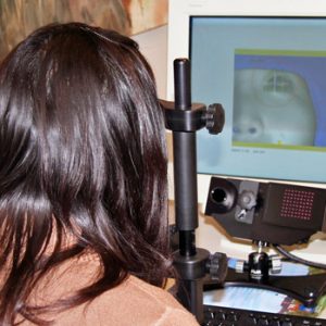 woman with eye tracker and face appearing on computer screen