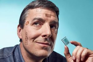 person with small electronics on face that look like tattoos