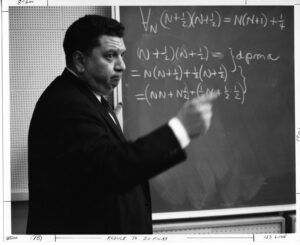Professor Max Beberman teaching math on a chalkboard.
